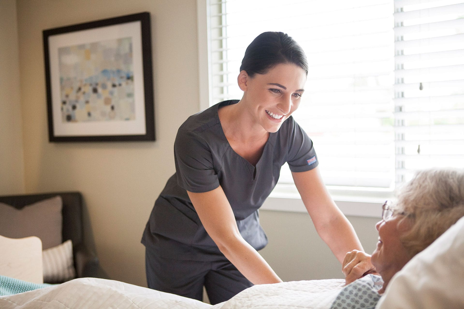 female nurse smiling while tucking in patient