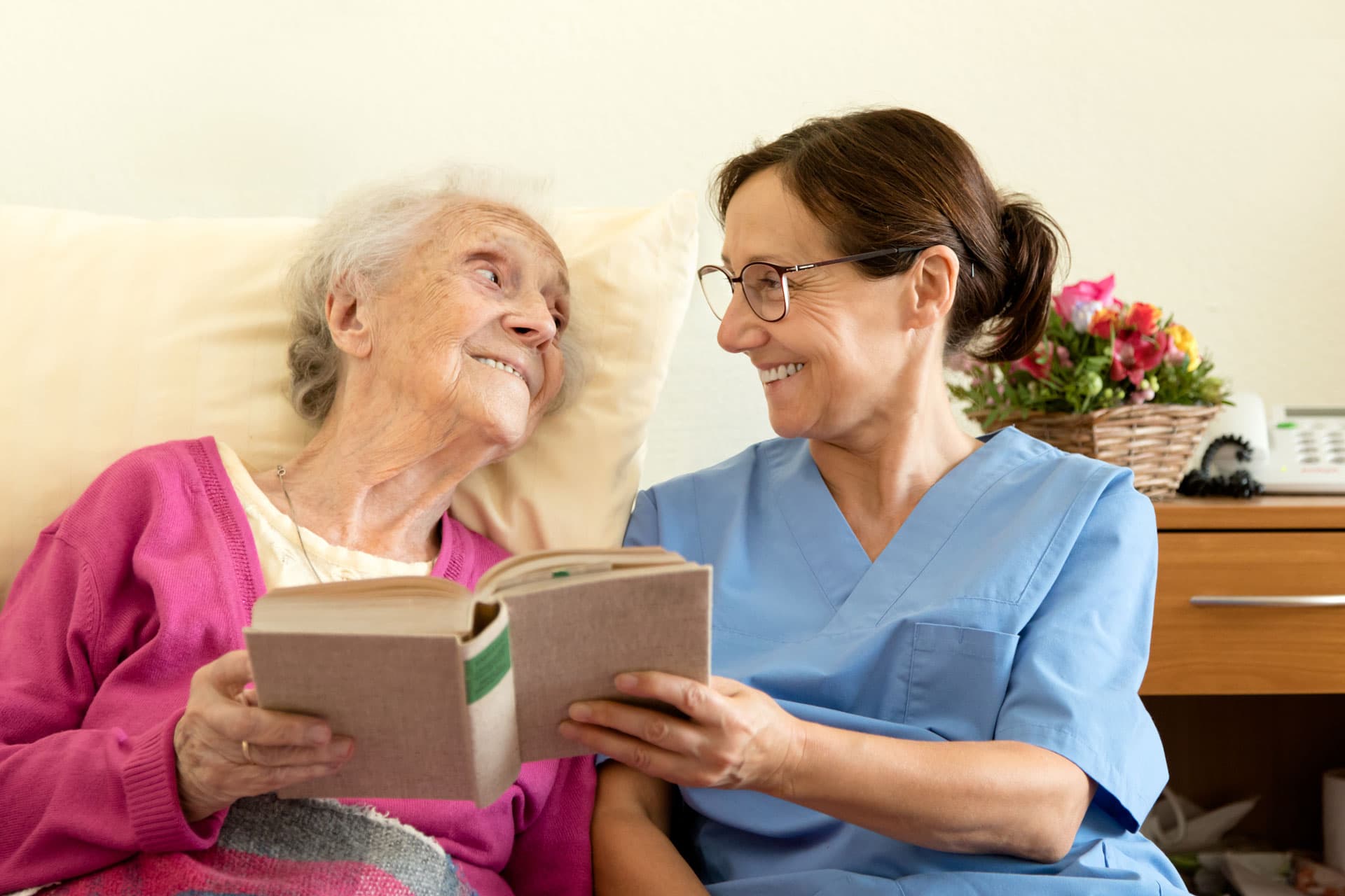 nurse reading a book to an senior patient