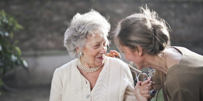 Skilled nurse smiling at elderly patient