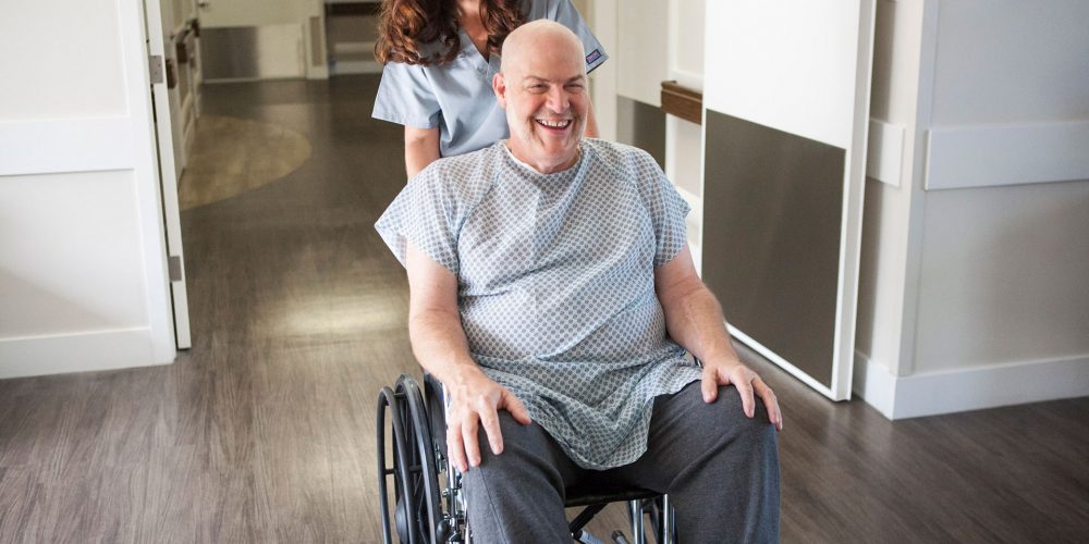 CNA pushing patient in wheelchair after surgery