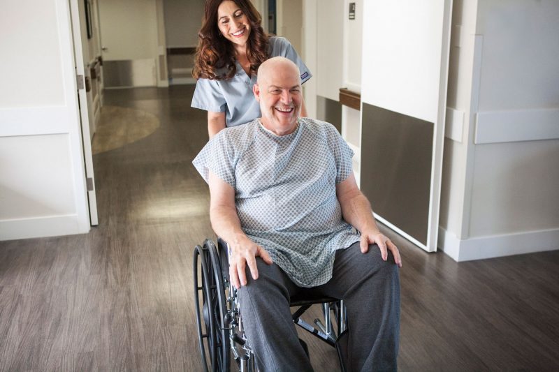 CNA pushing patient in wheelchair