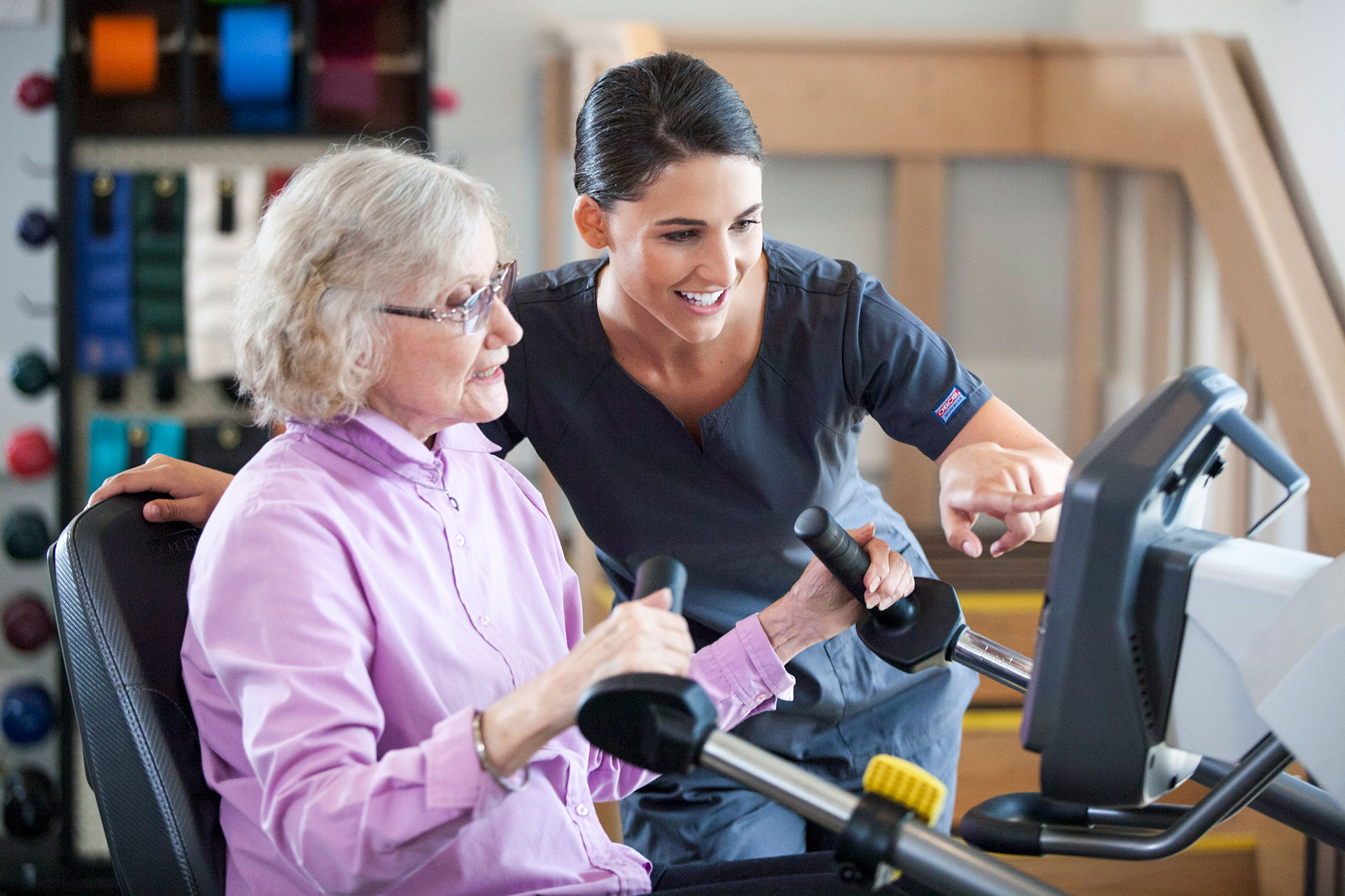 Physical therapist helping woman use equipment