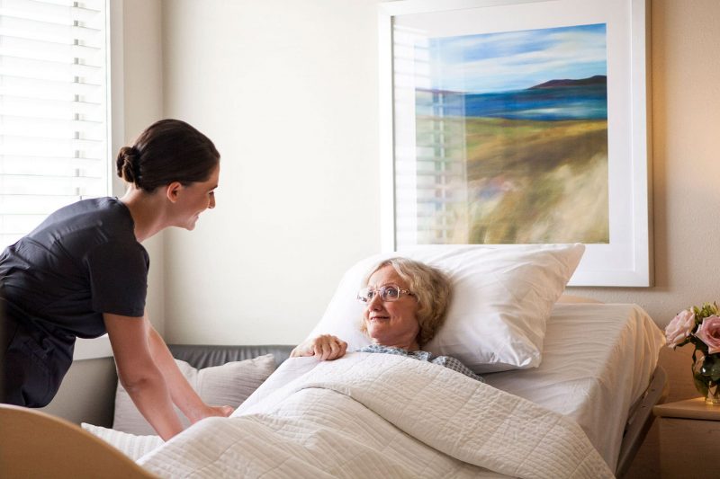 Skilled nurse caring for patient in bed