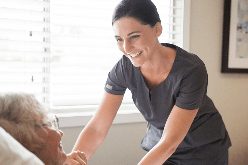 female nurse smiling while tucking in patient