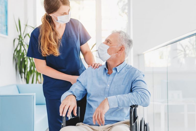 Skilled nurse helping patient in wheelchair