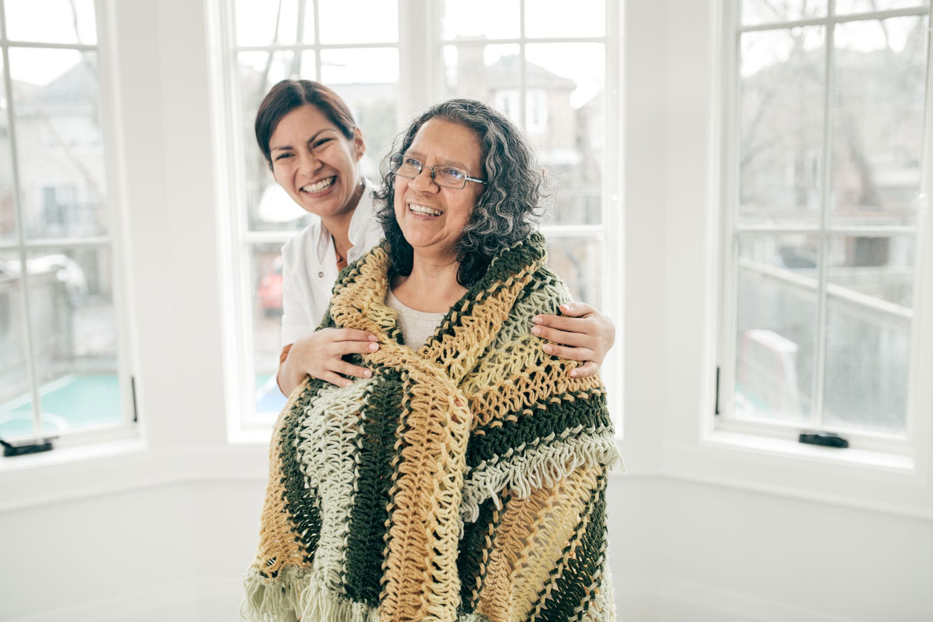 nurse wrapping older woman in a blanket