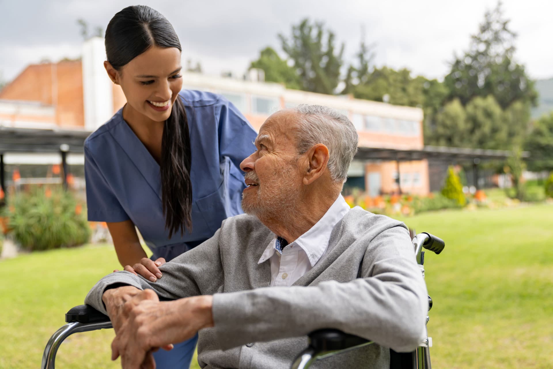 certified nurses assistant talking with wheelchair patient outdoors