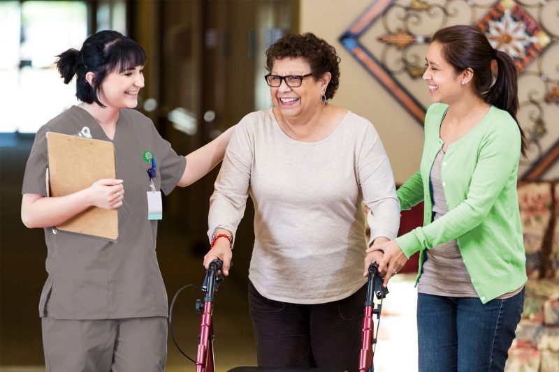 Registered nurse checking on a patient who is walking with a walker and her daughter