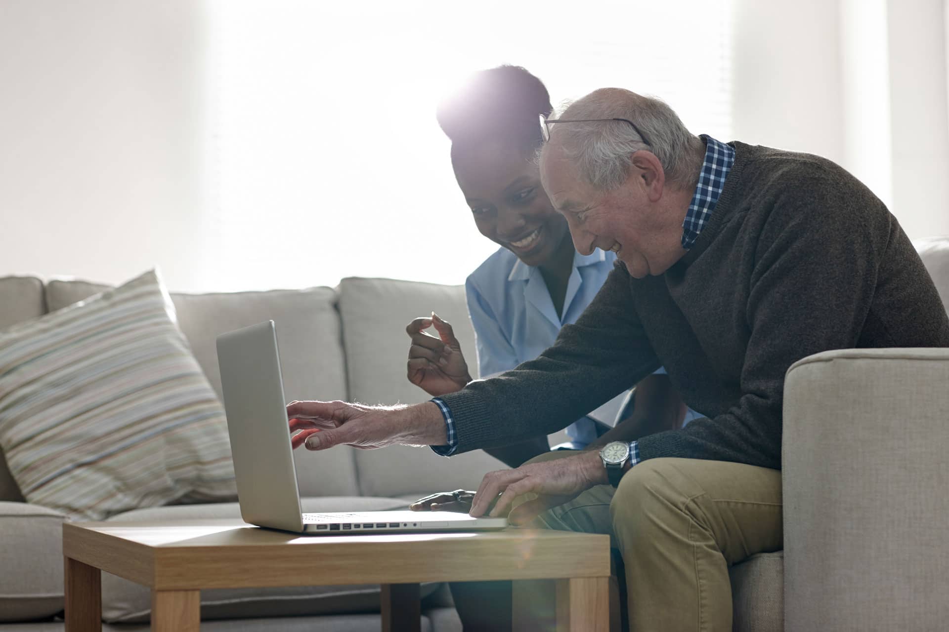 nurse assisting elder man with his laptop