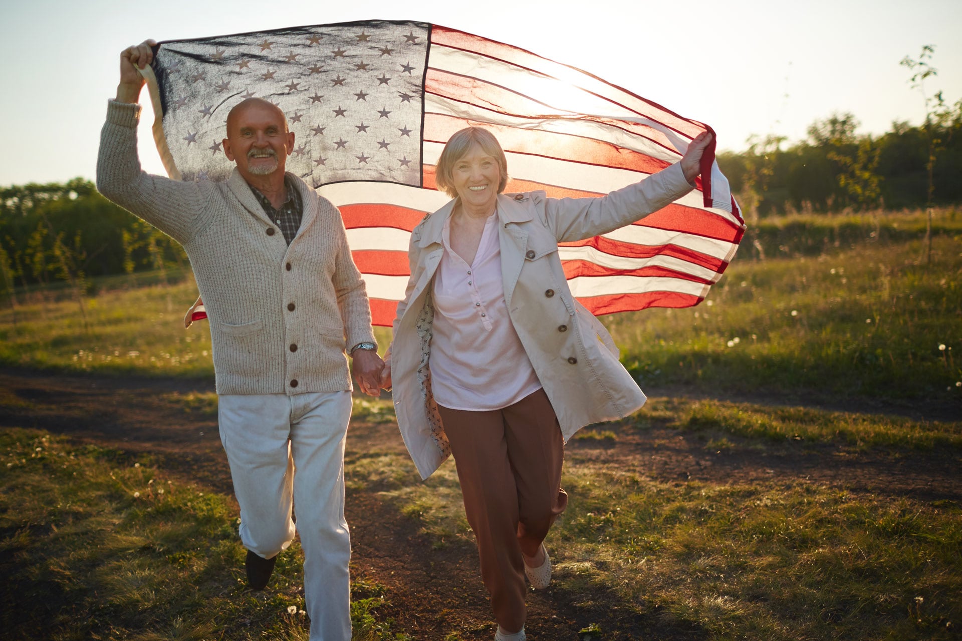 elder couple walking in the park with an American flag