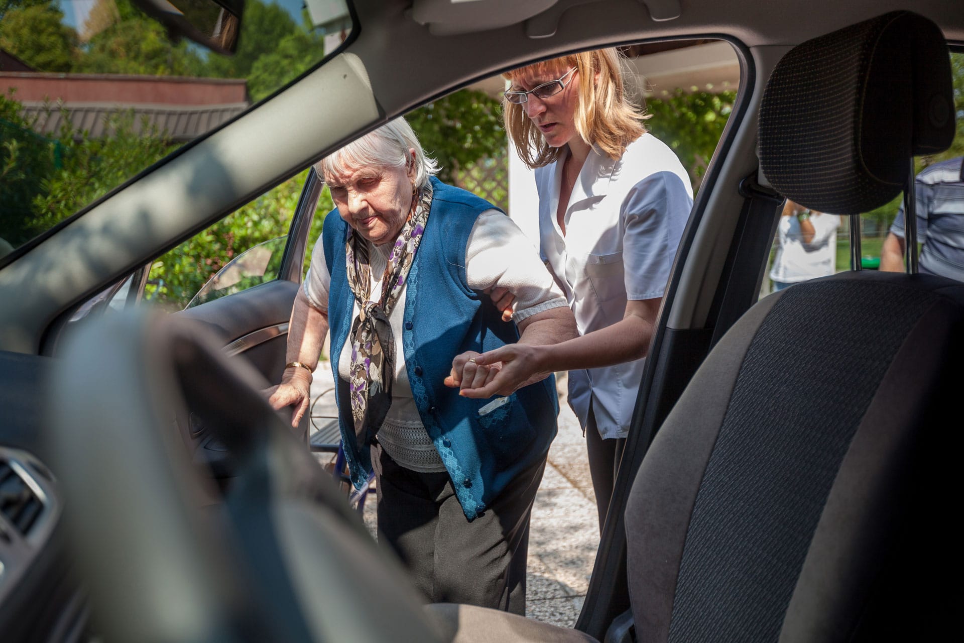 CNA helping patient into car