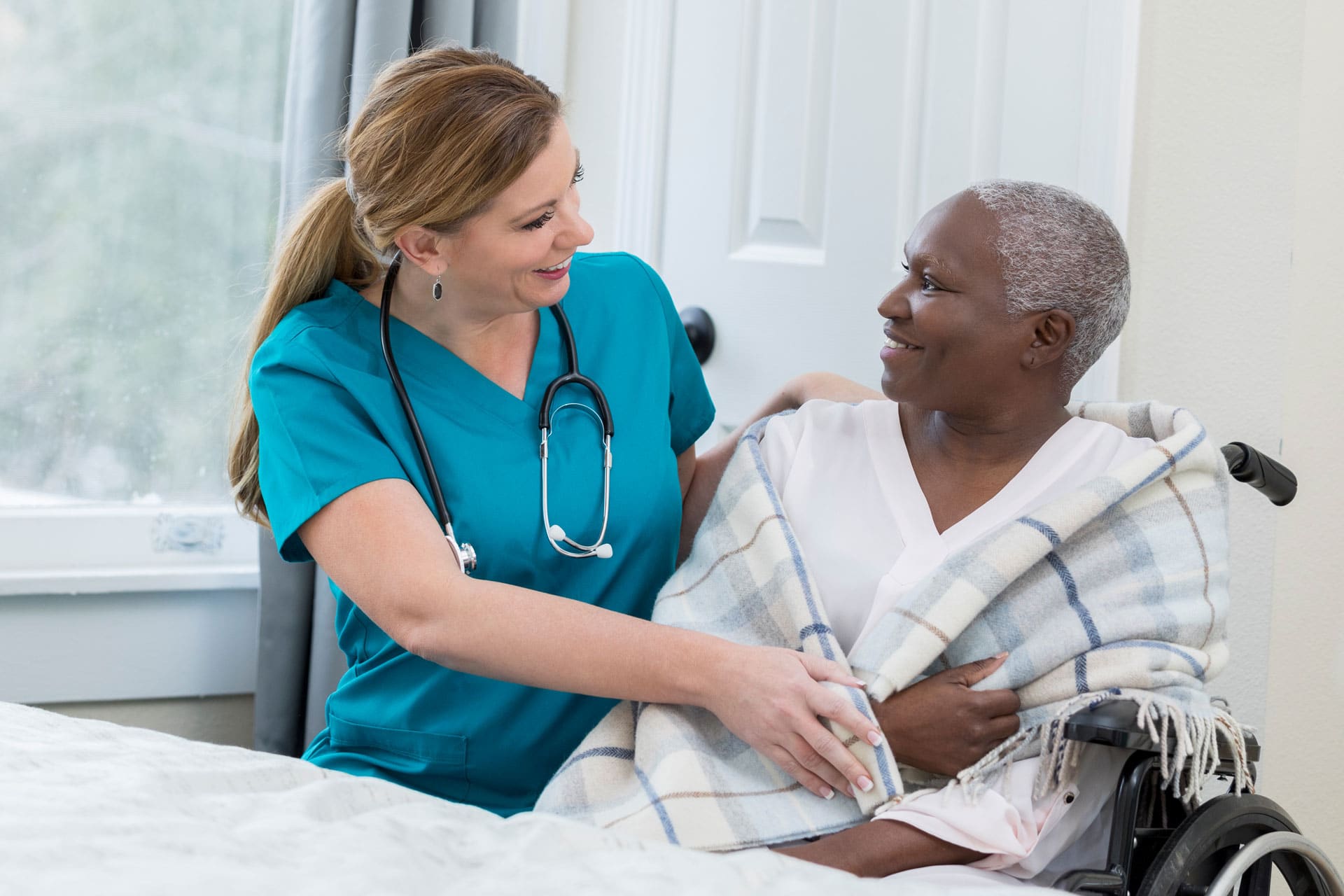 female skilled nurse checking in on elder patient in a wheelchair