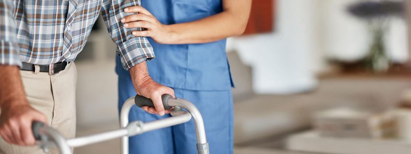 Skilled nurse helping man with walker