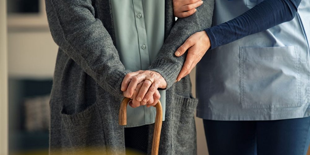Nurse Assisting Elder Patient Walk With A Cane
