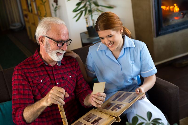 skilled nurse showing a dementia patient his family photos book