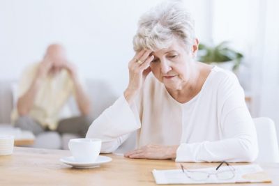 Older woman looking confused or depressed while sitting at table alone