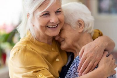Woman hugging older woman and smiling