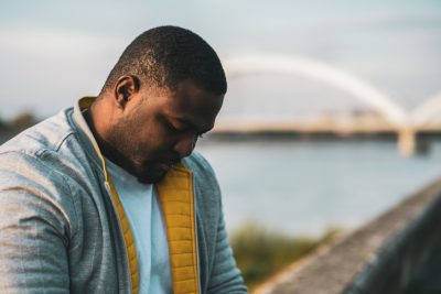 Depressed black man sitting outside 