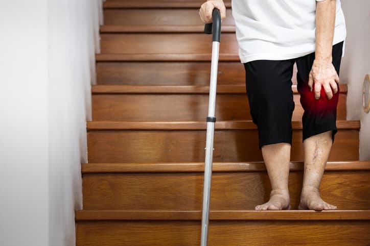 Elderly woman with knee pain going down stairs