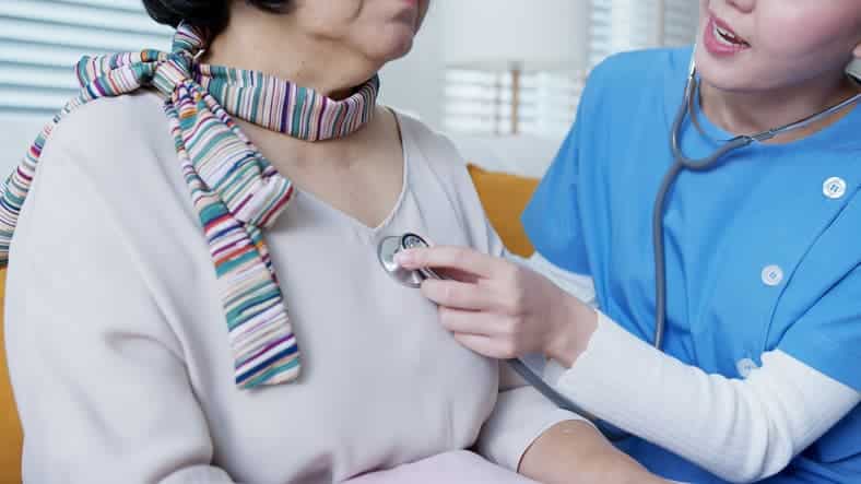 nurse listening to heart of older woman