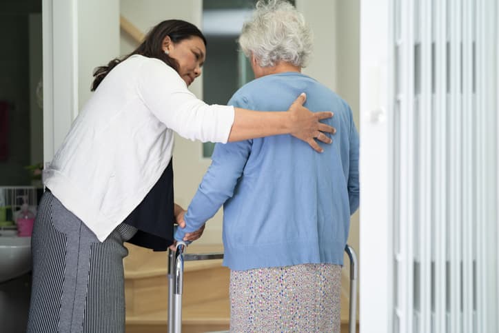 Caregiver Helps Elderly Old Woman Walk With Walker