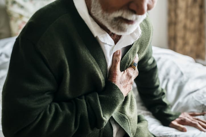 Elderly man holding heart in pain