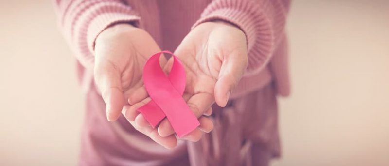 Woman Holding Pink Ribbon In Hands For Breast Cancer Awareness