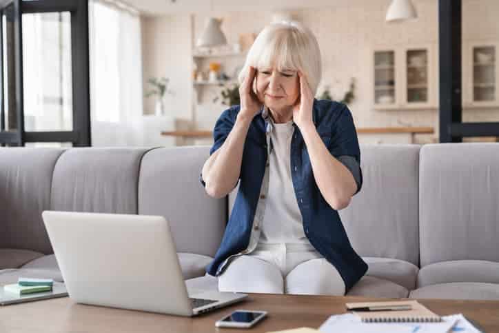 Older woman with headache sitting on couch