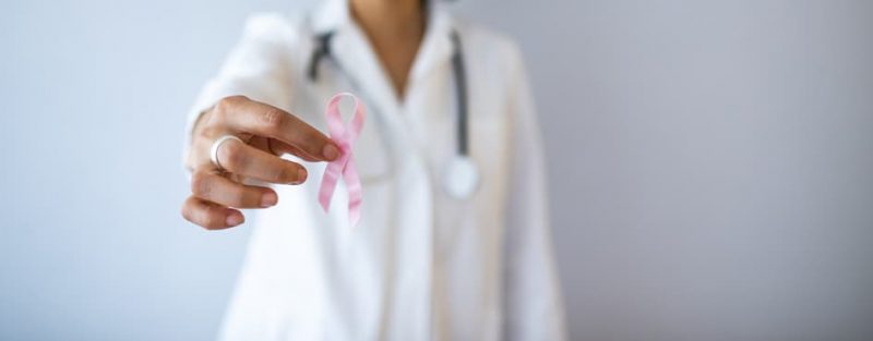 Doctor holding pink ribbon for breast cancer awareness