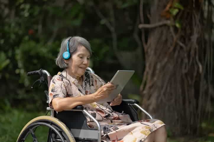 Elderly woman in wheelchair listening to music