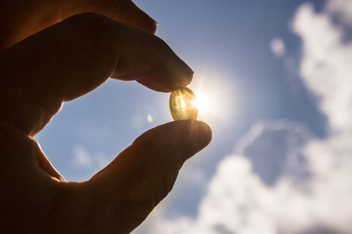 holding capsule of vitamin D in the sunlight
