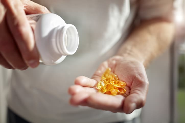 man pouring vitamin d capsules into hand