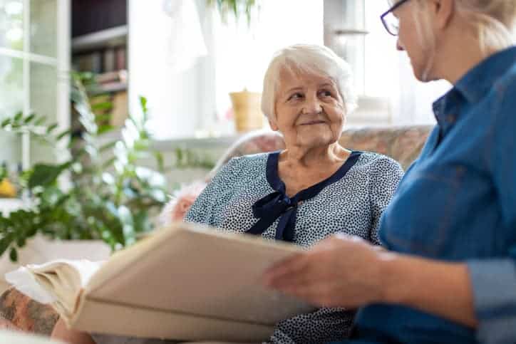 Elderly woman looking at book with another woman