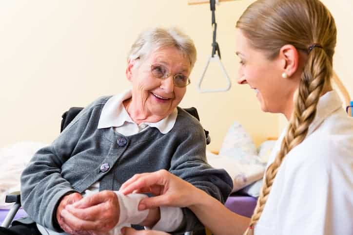 Nurse helping elderly patient with bandage for wound care