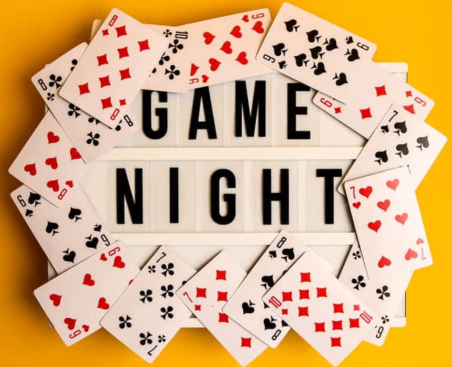 a sign stating, "game night," that is surrounded by playing cards.