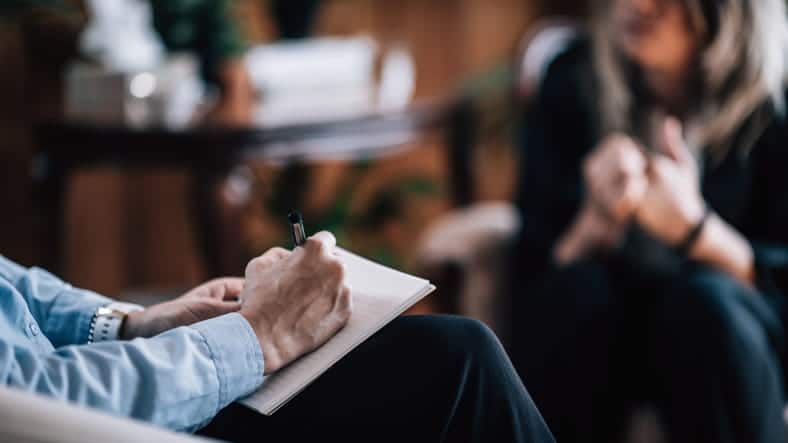 focus is on a therapist using CBT therapy on their client who is blurred out in the background.