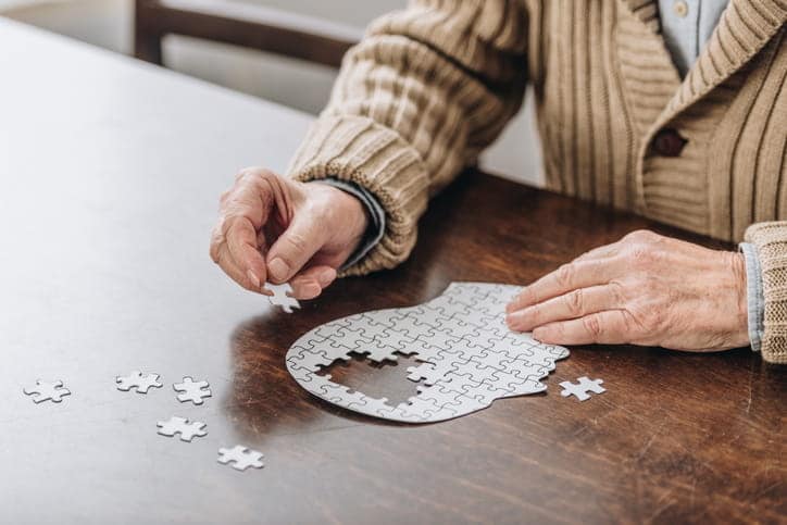 An elderly man doing a puzzle.