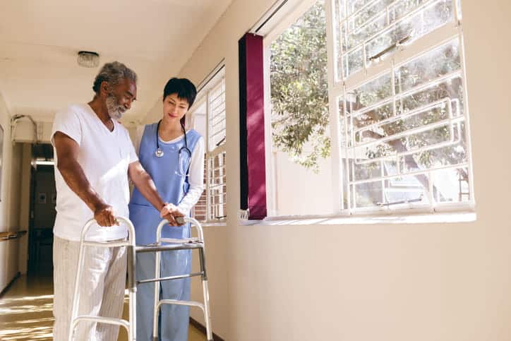 A female CNA helping an elderly male patient after completing their CNA training in Arizona.