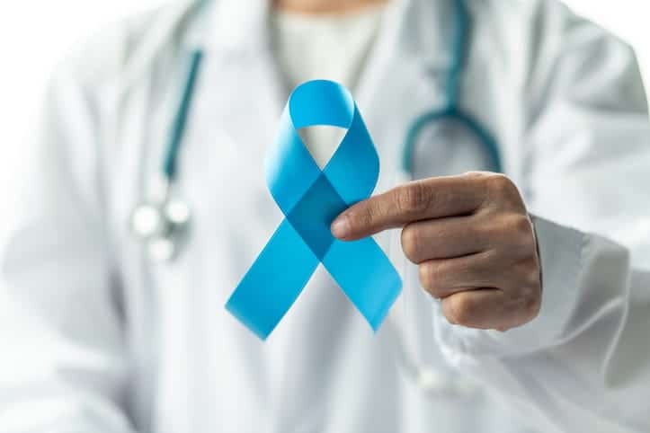 A doctor out of focus, holding a blue ribbon with one hand that represents prostate cancer.