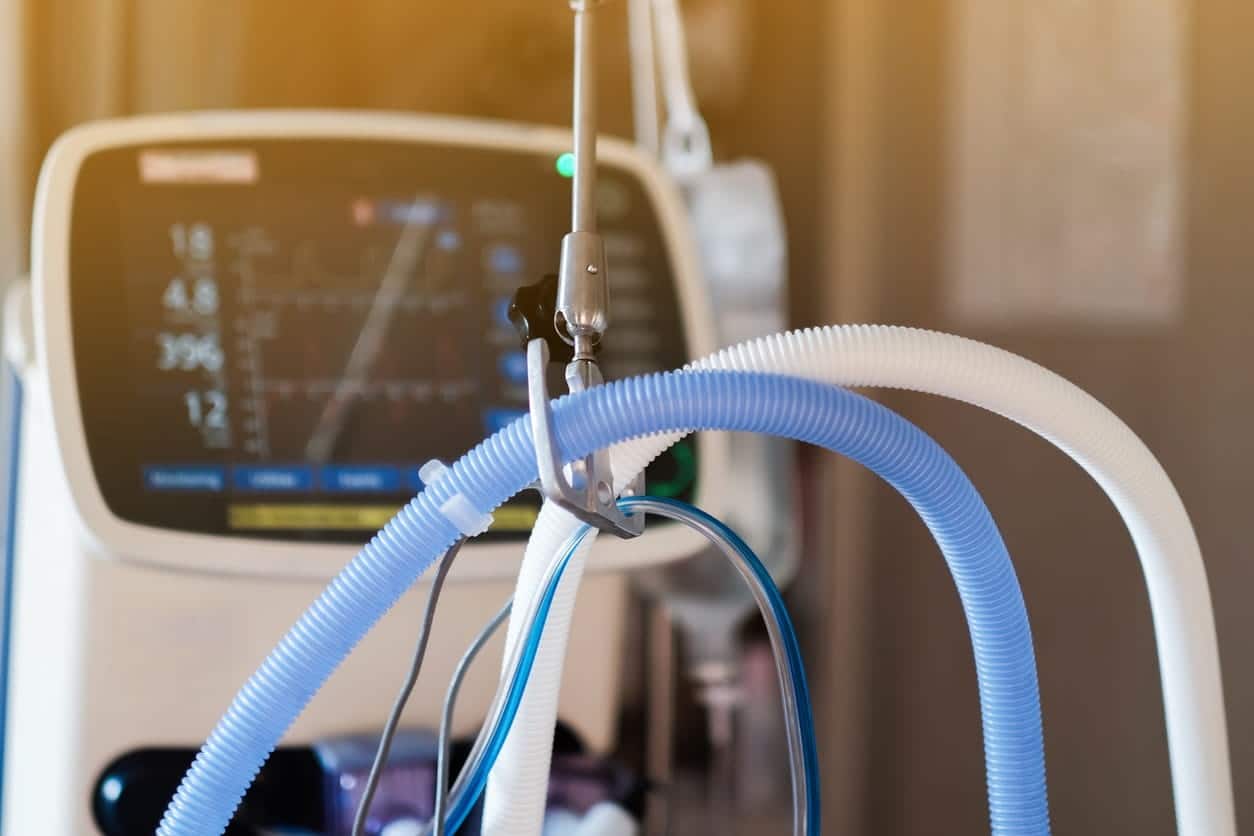 A close up of ventilator tubes, with the machine in the background.