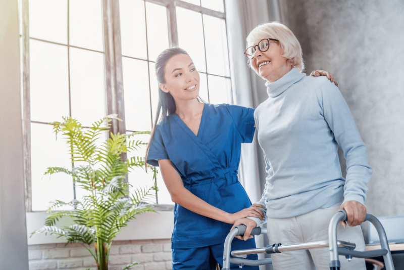 A Nurse Assisting A Patient With A Walker Inside Haven Health Facilities.