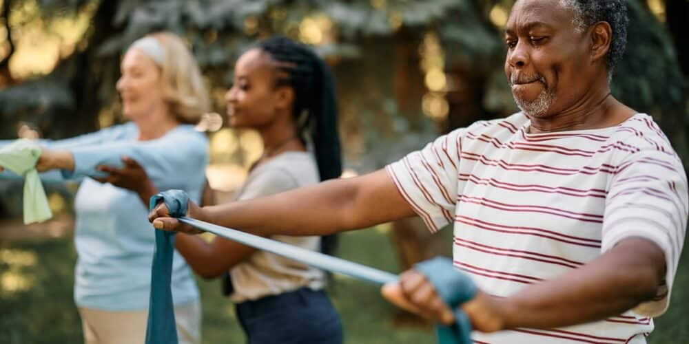 An aid helping two seniors with their exercises.