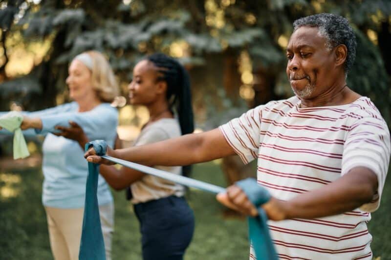 An Aid Helping Two Seniors With Their Exercises.