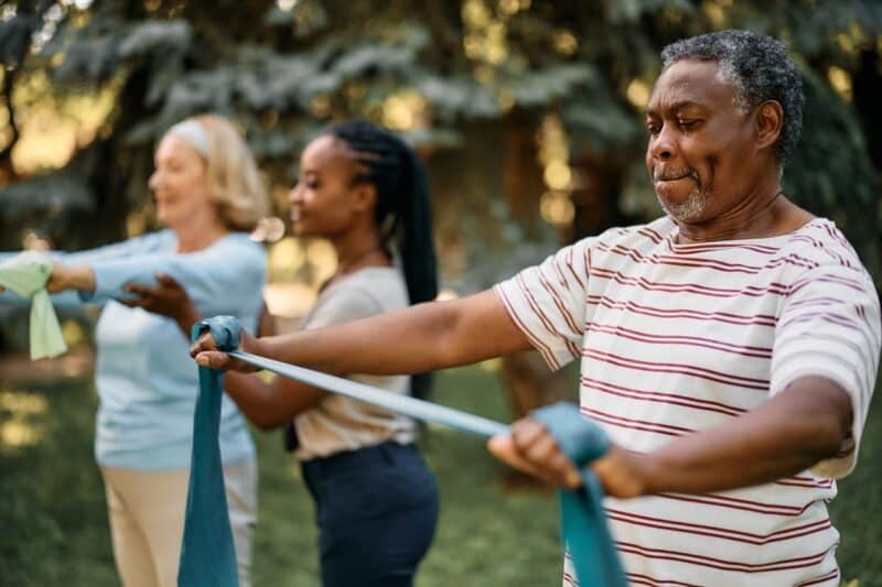 An aid helping two seniors with their exercises.