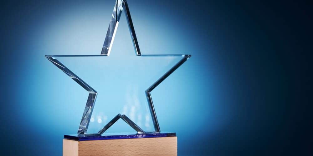 A glass award in the shape of a star on a wooden block.