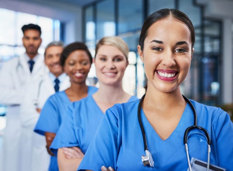 A line of five nurses and doctors in a row, smiling for a photo in Arizona. 