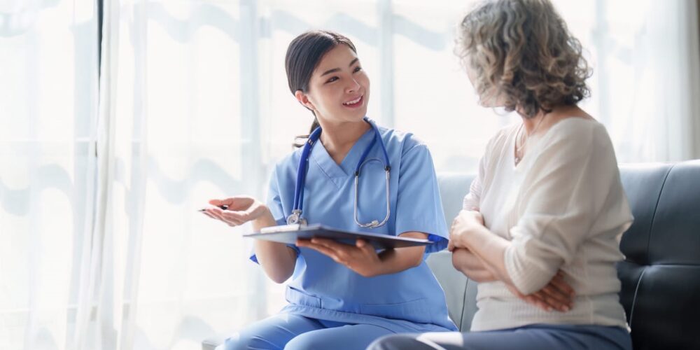 A Certified Nursing Assistant Helping A Patient With Their Paperwork.