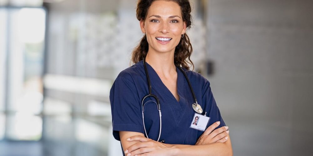 A nurse with her arms folded, smiling for a picture.