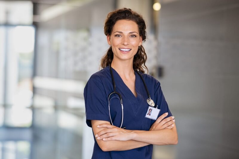 A nurse with her arms folded, smiling for a picture.