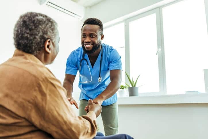 A male nurse assisting an elderly patient at an assisted living facility. 